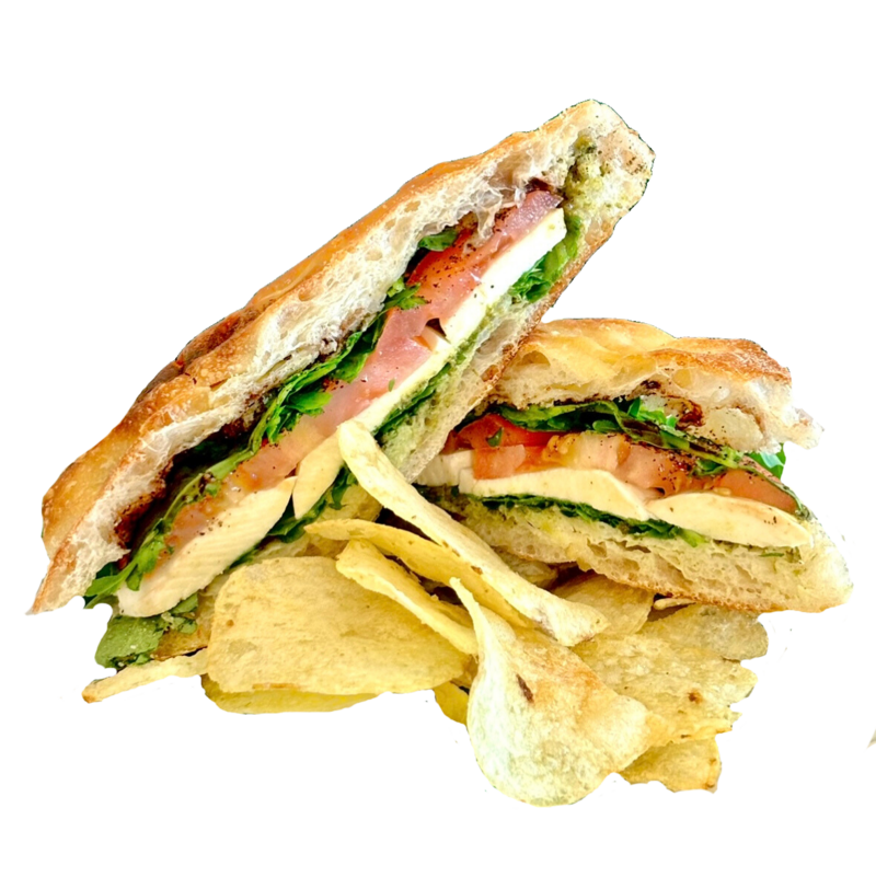 Caprese sandwich with mozzarella, tomato, basil pesto, and greens, served with chips on a plate at Lyla's House in Georgetown, ON.