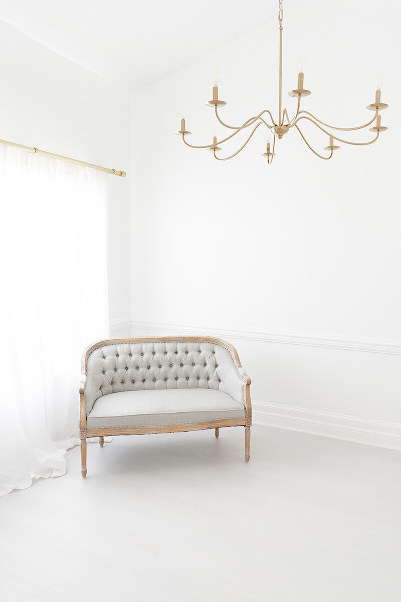 Bright and airy natural light studio with tufted sofa and chandelier at Andrea Krey Photography in Destin, FL