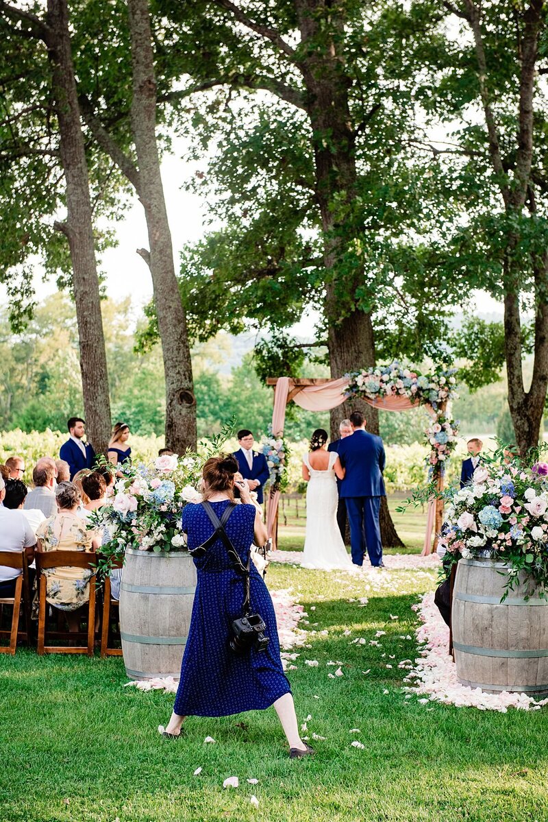 Behind the scenes photo of a photographer taking images during an outdoor ceremony at a vineyard