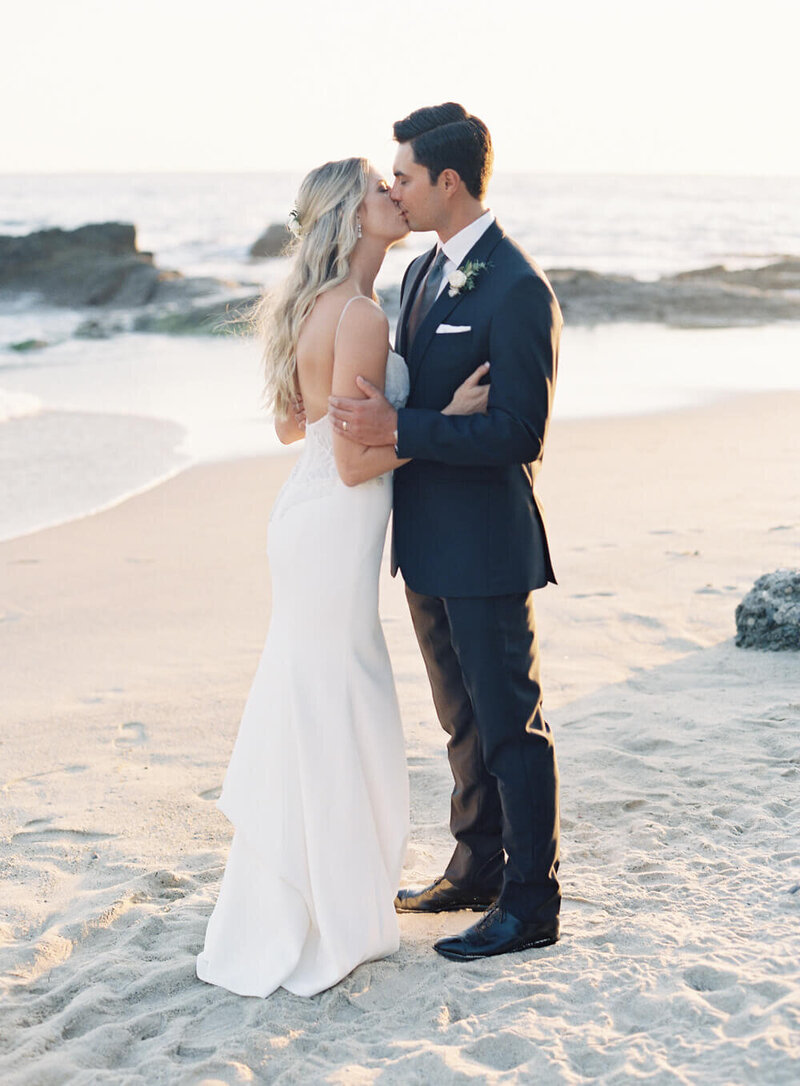 Bride and groom kiss on a beach at Montage Laguna wedding in California with San Diego Jacqueline Benet Photography