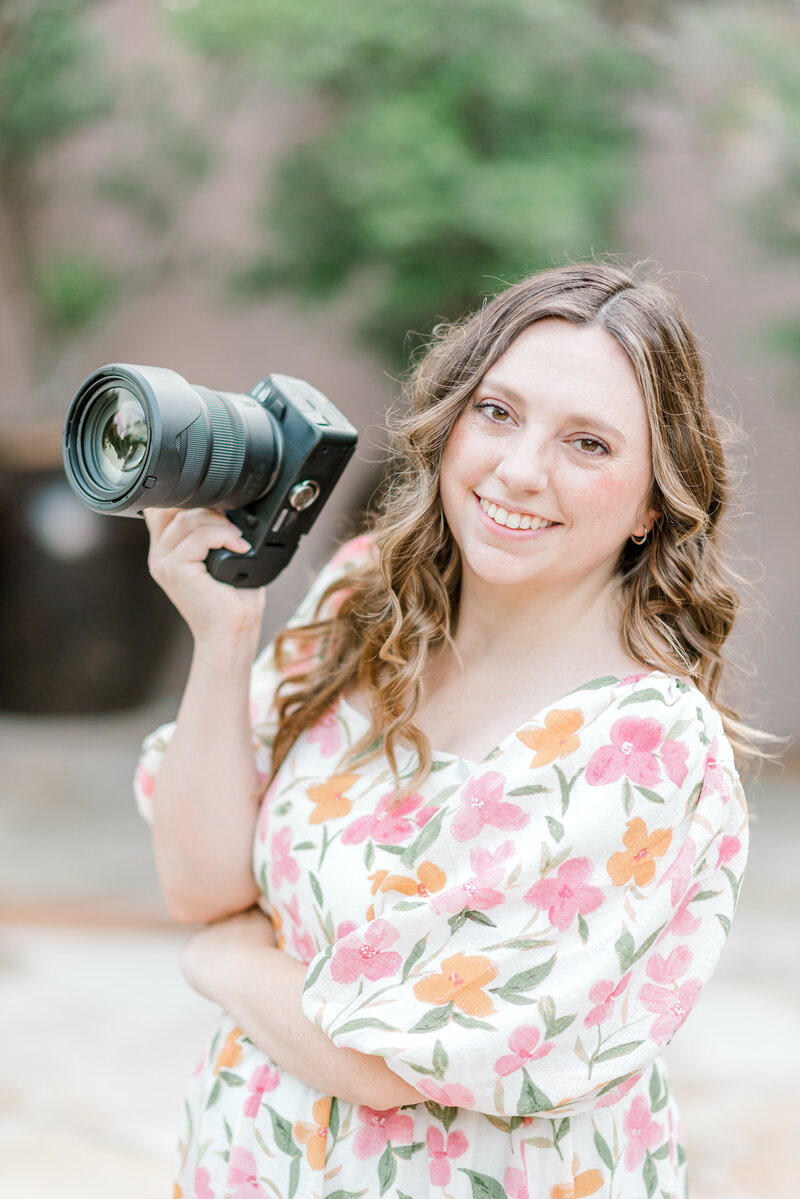 top san antonio wedding photographer standing for a photo holding her camera smiling