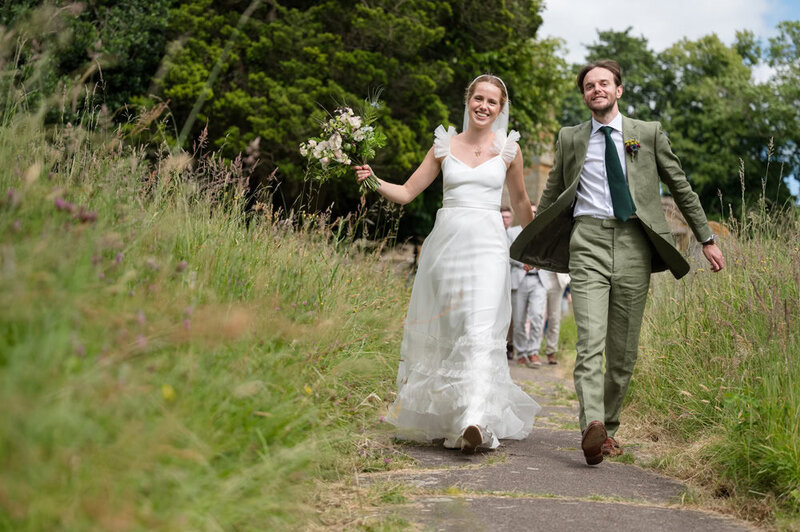 Bride and groom walking joyfully down church path 