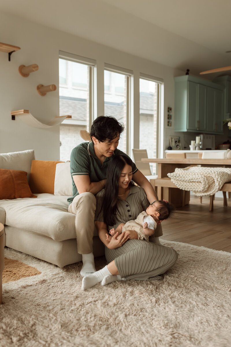 Mom and dad sitting while mom is holding her newborn in her arms