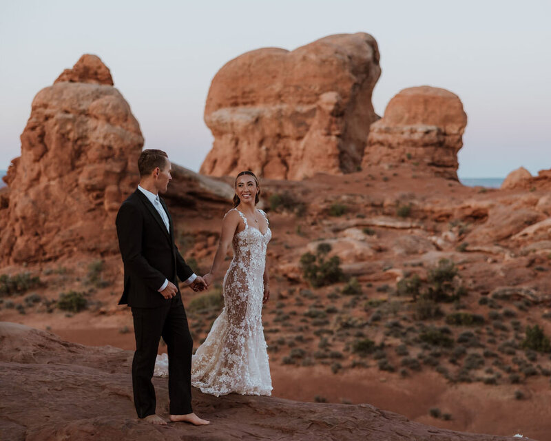 bride and groom walking and holding hands in arches national park