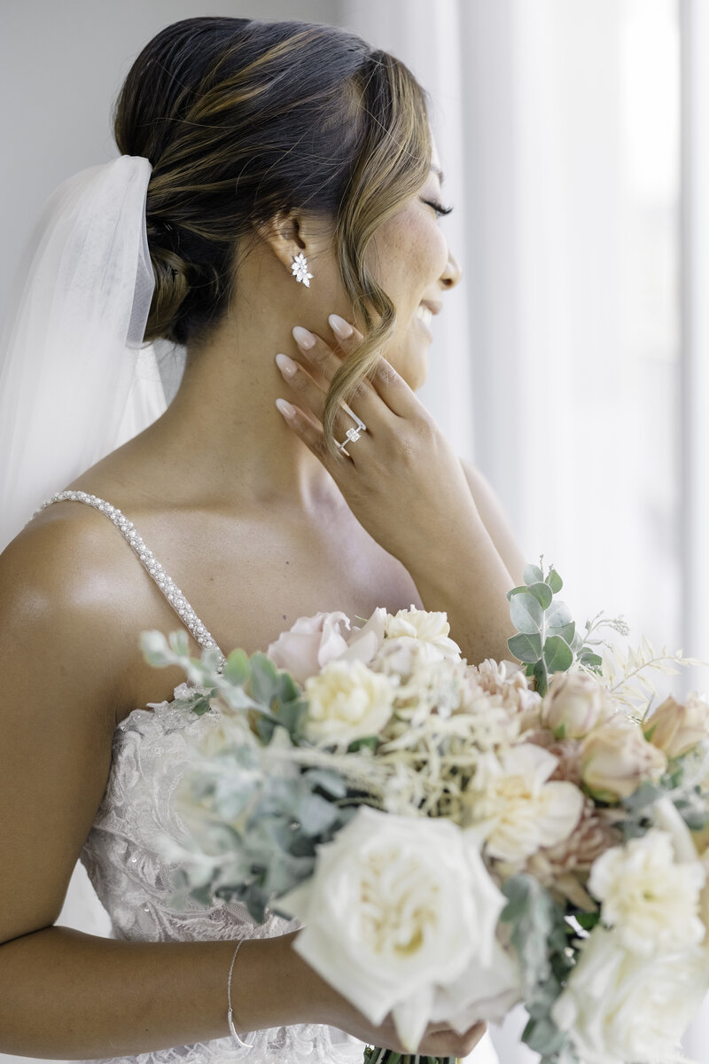 bride smiling out of a window with her bouquet in foreground