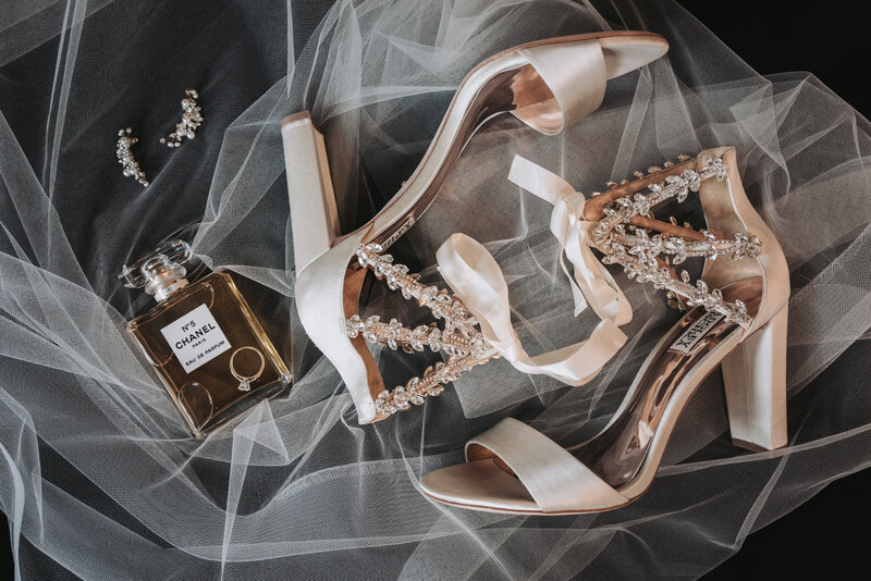 Close up detail shot of the brides heels and perfume laying on her veil