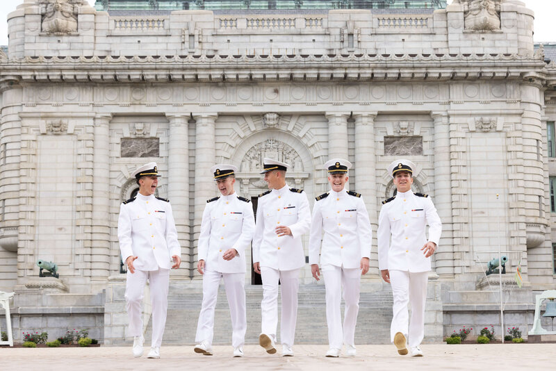 group of 5 midshimen in white uniforms laughing and walking  at USNA in Annapolis Maryland