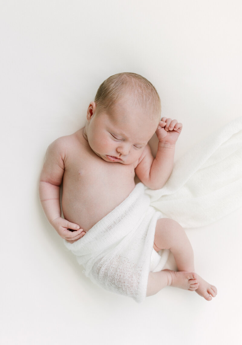 Newborn Photographer,  an image of a baby sleeping, wrapped  in a blanket