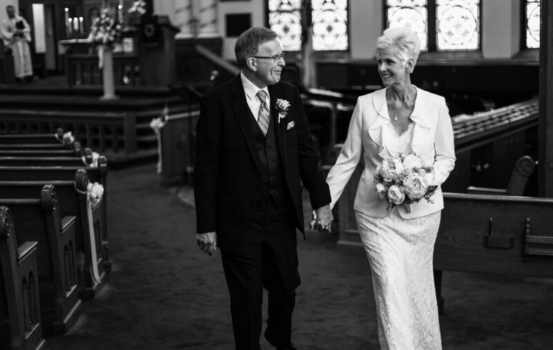 Recessional photo of bride and groom walking hand-in-hand at the end of their wedding ceremony at St. John's Lutheran Church in Erie, PA
