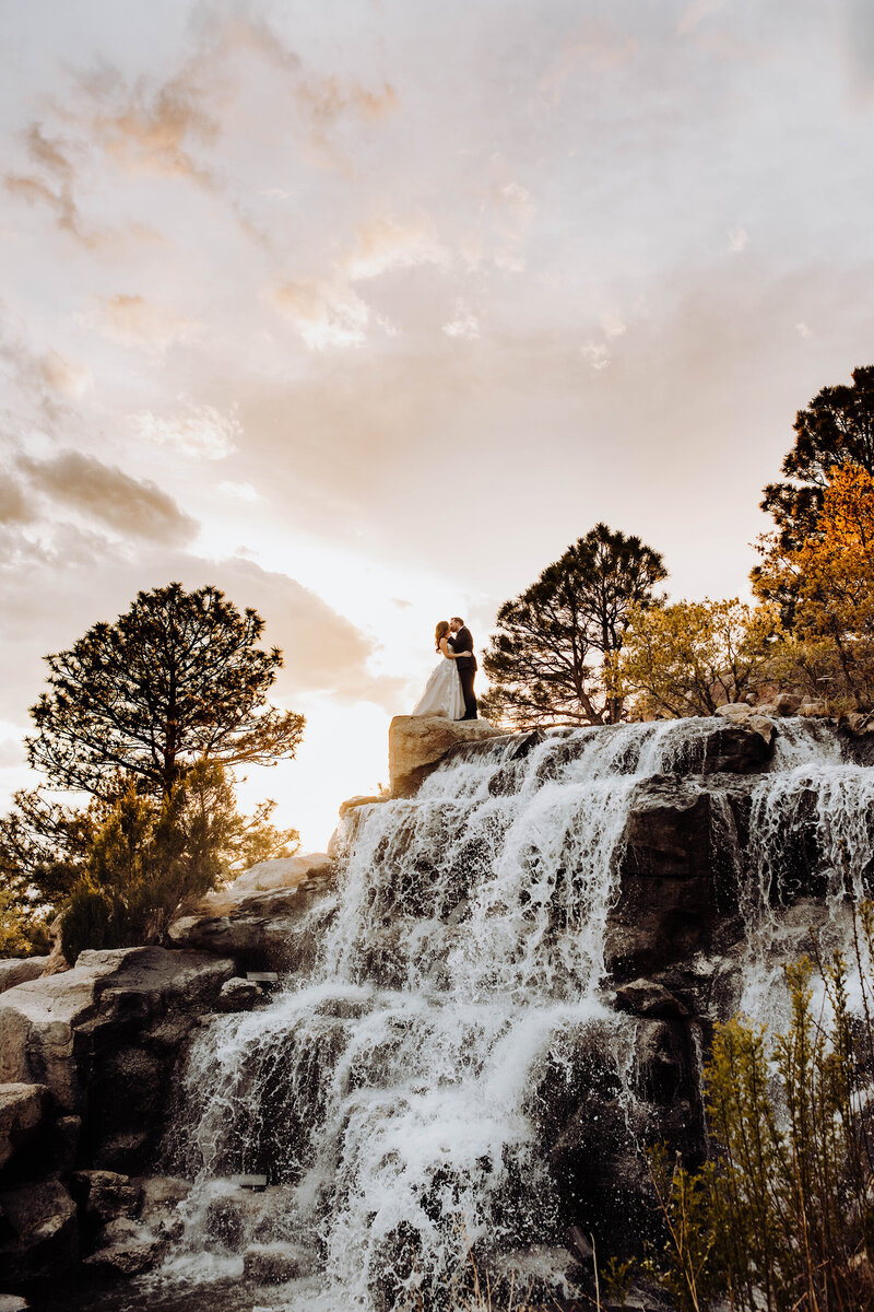 bride-groom-kissing-top-of-waterfall