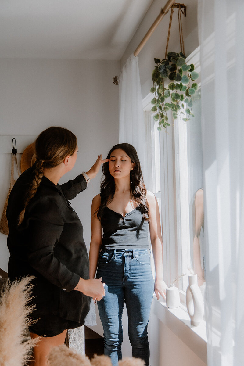 a woman doing a models makeup in a portrait studio