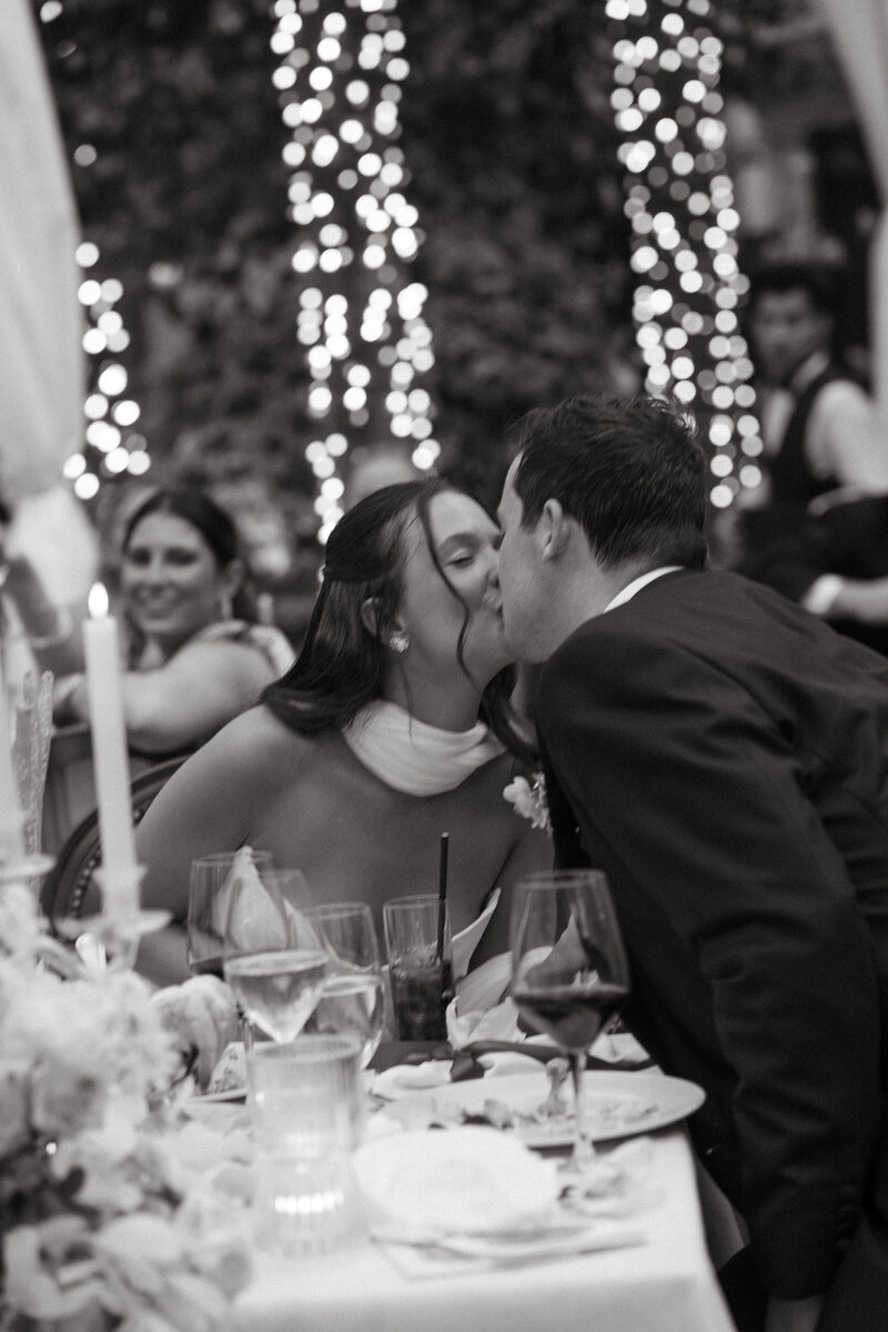 A couple kisses at their sweetheart table