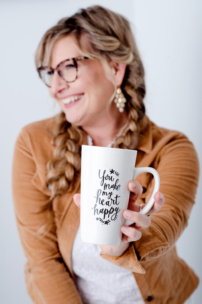 Kat Jones holding a coffee mug that reads, You Make My Heart Happy
