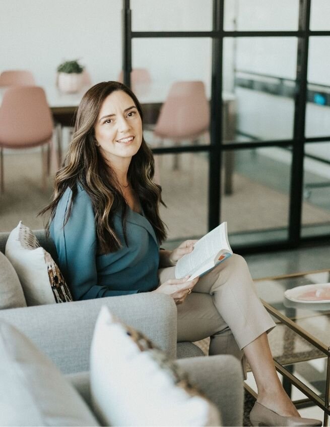 Idit sits and smiles as she reads a book in her therapy office. Her Miami, FL based therapy practice offers couples therapy programs in Florida. Contact her team for a couples therapist that can support you!
