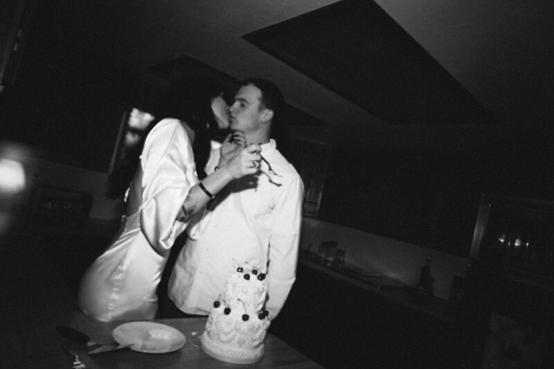bride and groom kissing while they eat their vintage wedding cake in Colorado