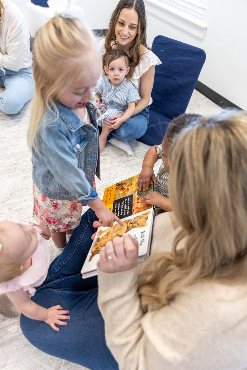 Two women reading a book to toddlers