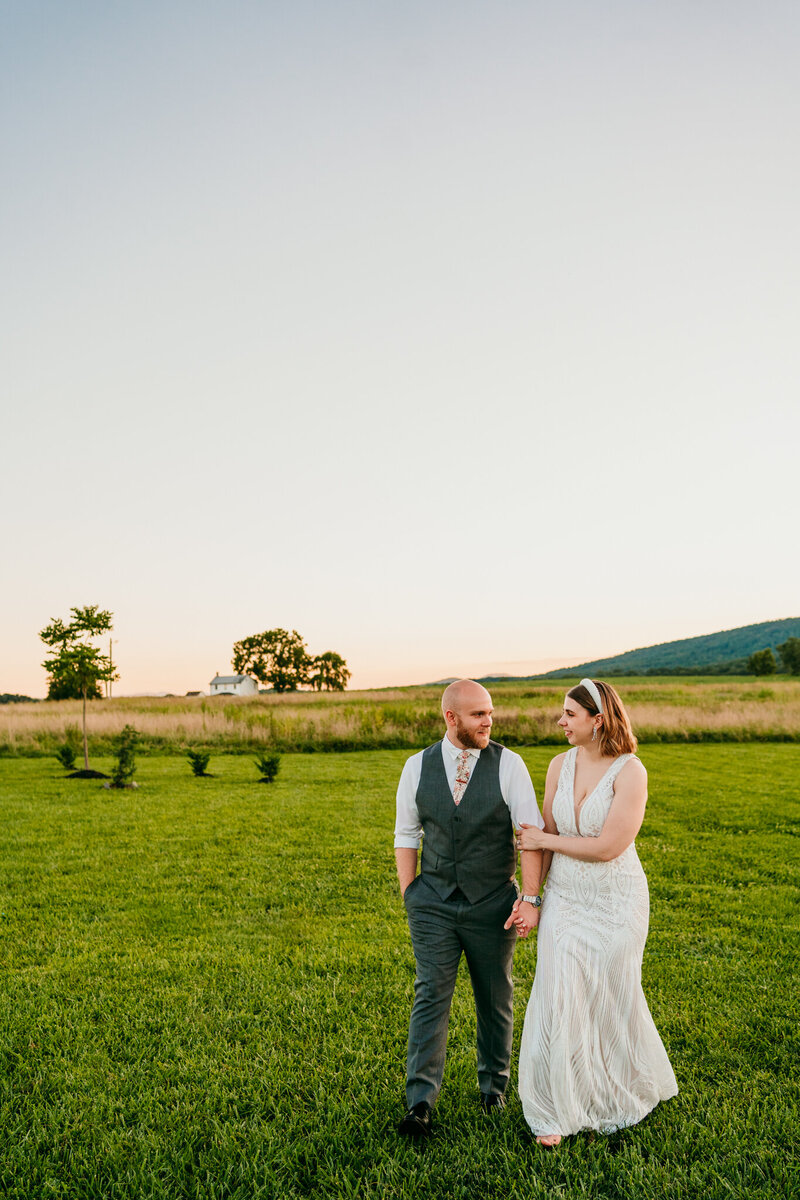 Eloping couple holding hands in open field with the Blue Ridge Mountains behind them at
sunset
