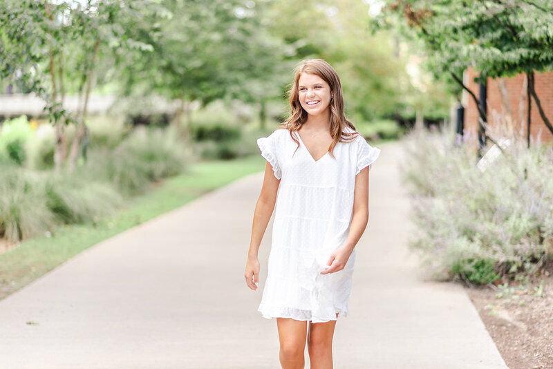 girl walking and smiling in Wilmington, NC during her senior photography session