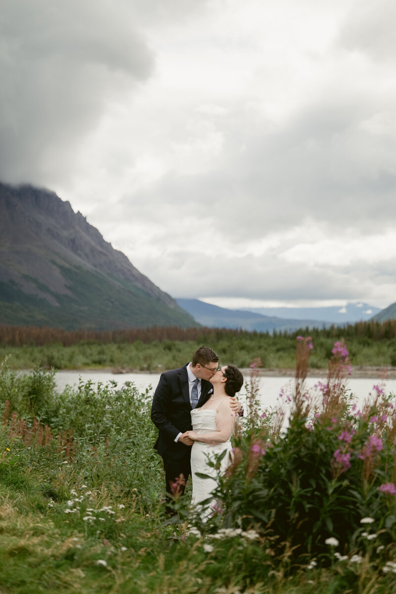a groom and bride kissing at their wedding in Denali Alaska in the mountains