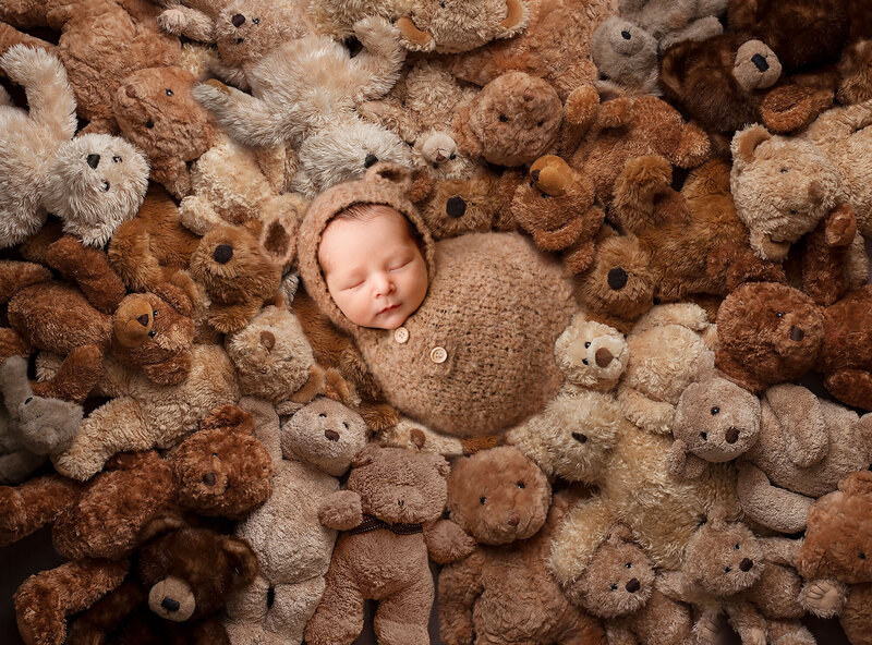 baby boy bear outfit surrounded by other stuffed bears in a