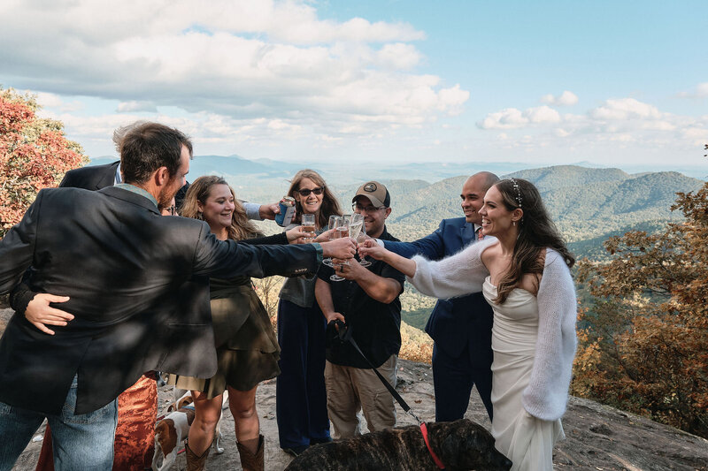 Eloping couple cheers with their families on a mountaintop