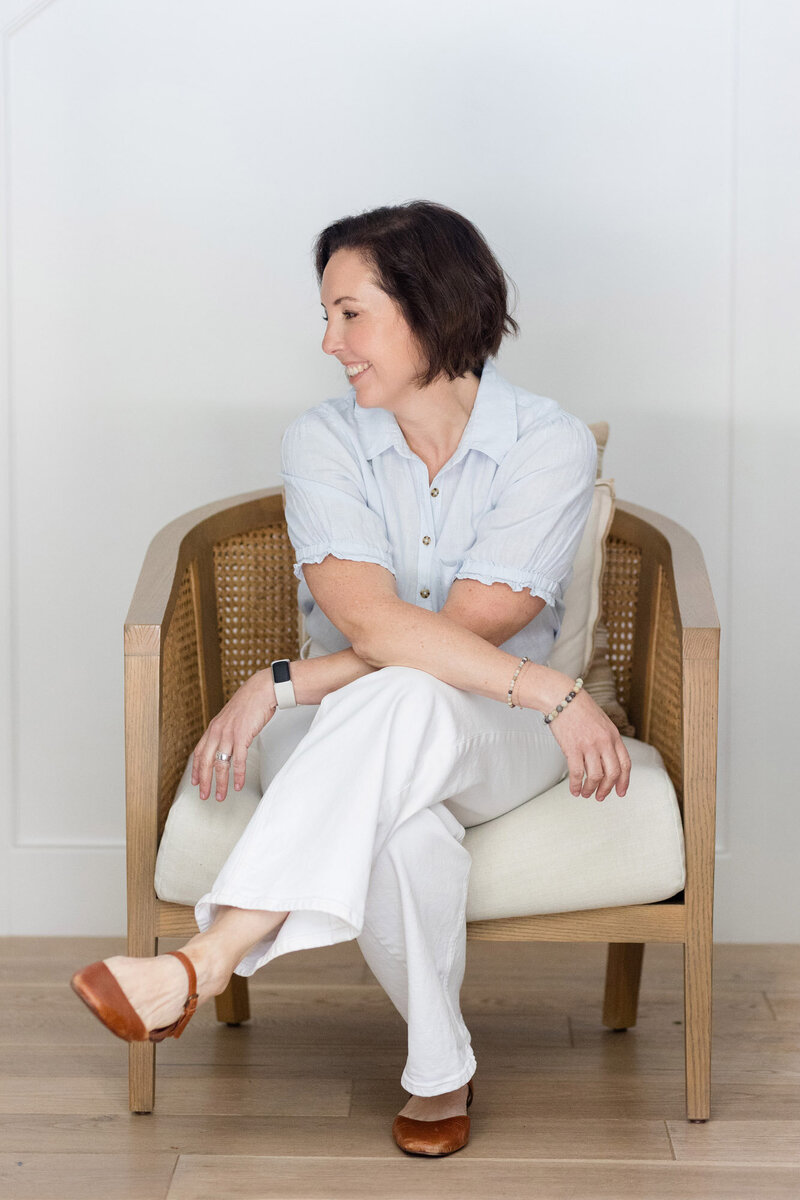 Life coach Dinah McBride sitting on a chair with her legs gently crosses, smiling