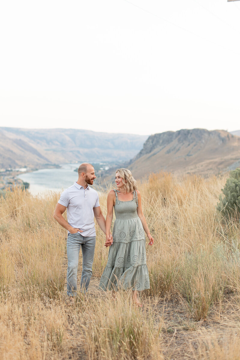 Toly Dzyuba is a wedding photographer known for capturing stunning photographs of his clients. The photograph captures them hand-in-hand while walking through the trails of State Washington and the beauty of Lake Chelan.