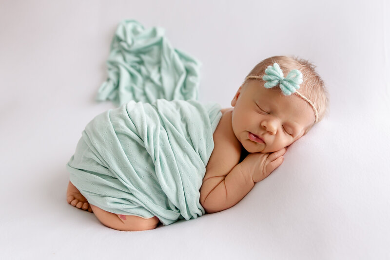Newborn photo in studio with baby wearing bonnet and smiling