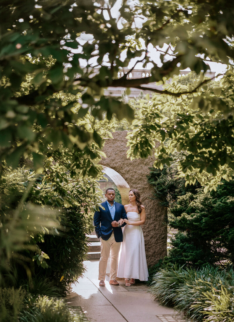 man-and-woman-standing-under-archway-with-greenery