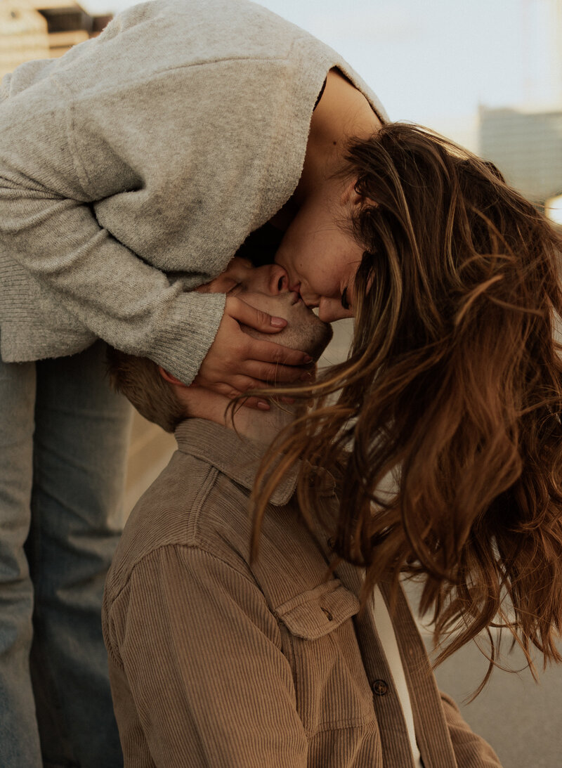 A photo of a girl leaning over a guy and kissing him
