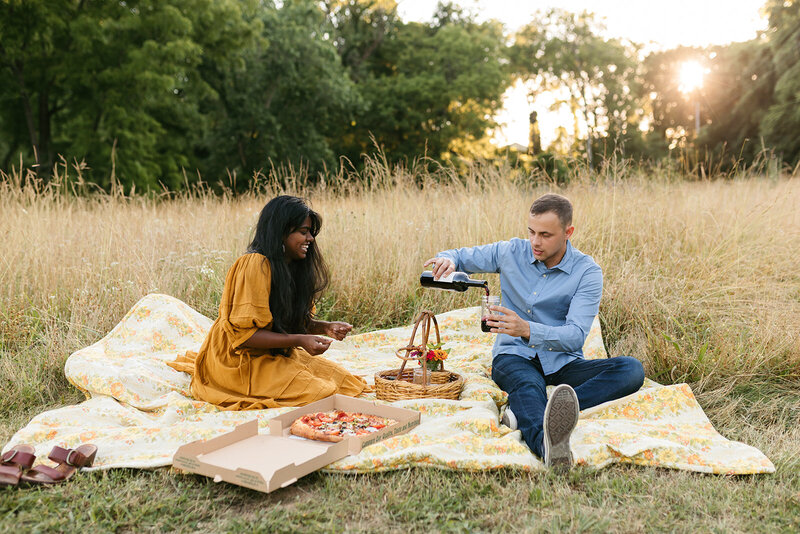 Couple having a picnic in a field during warm, vibrant Nashville engagement session