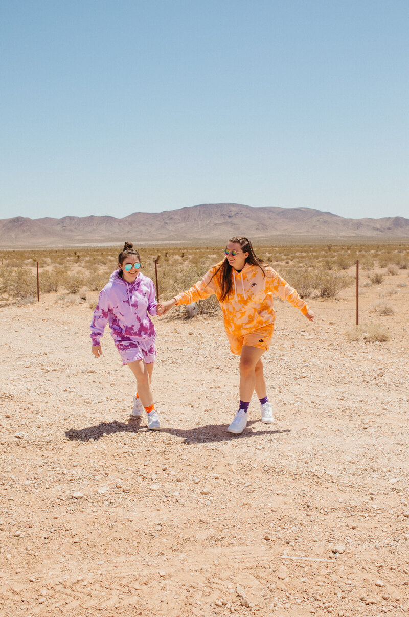 Two girls holding hands in the desert.