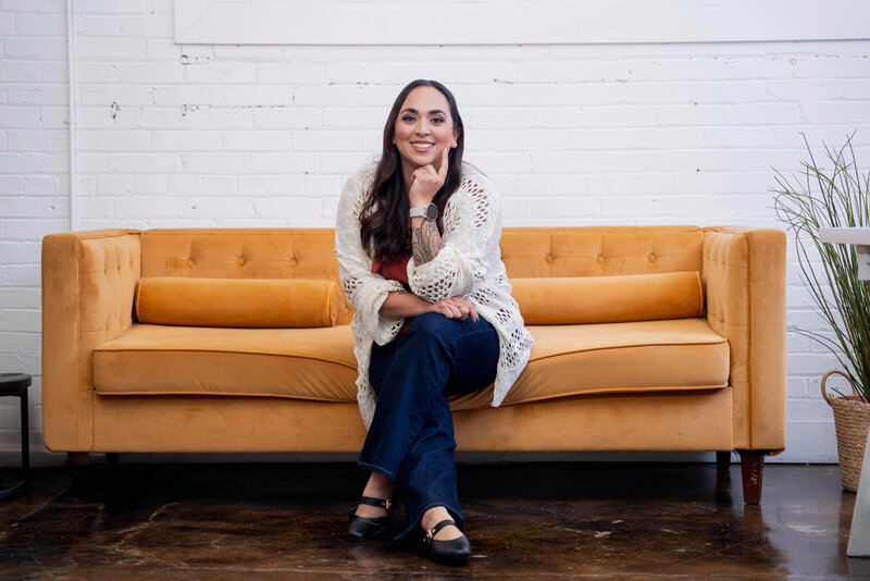 Stephanie, Founder of BCWise Consulting, sitting on a yellow sofa 