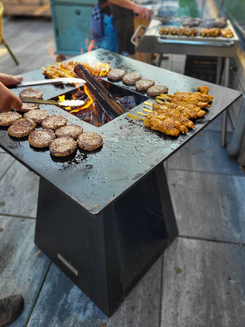 Medewerker grilt vlees tijdens een gezellige buitenbarbecue bij ’t Twents Kwartiertje.