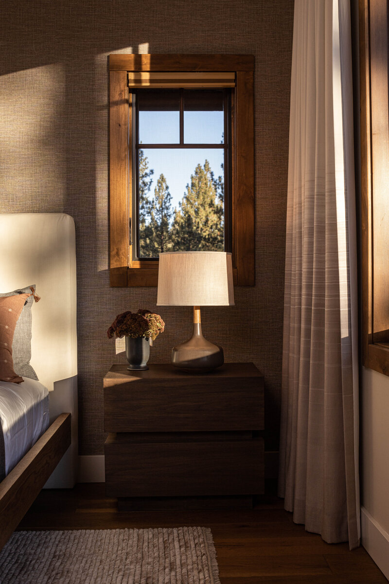 Interior design photography of a cozy bedroom with a window and bedside lamp.