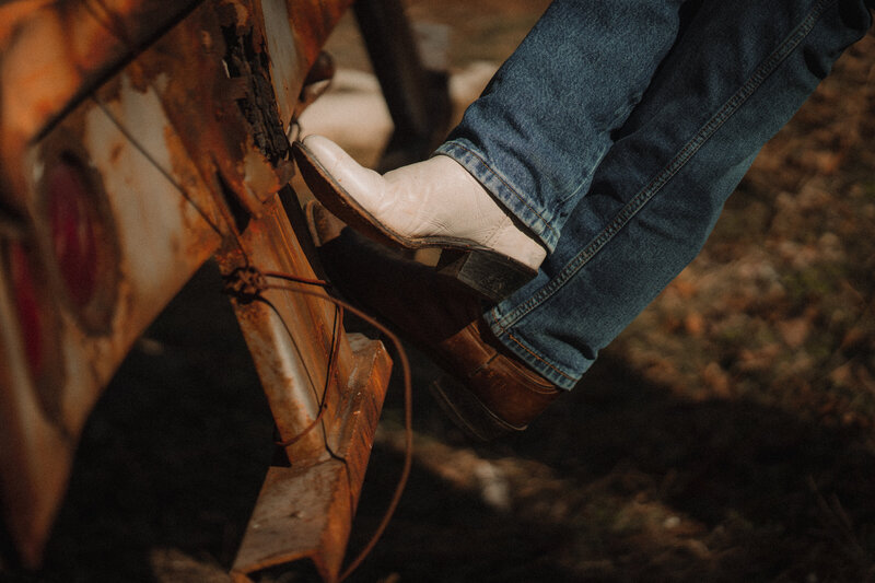 Black and brown cowboy boots cross over each other while propped up against a semi-truck.