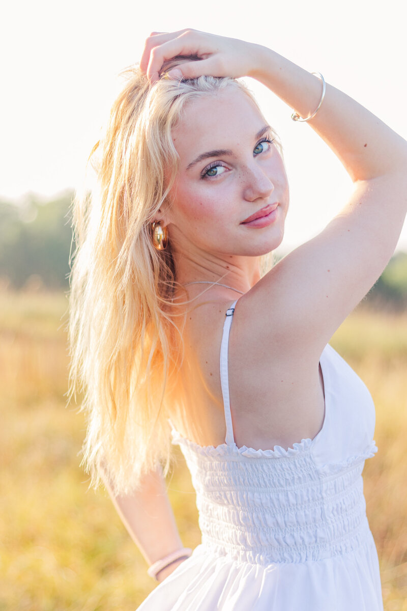 Blond girl in white dress bathed in golden light looking over her shoulder