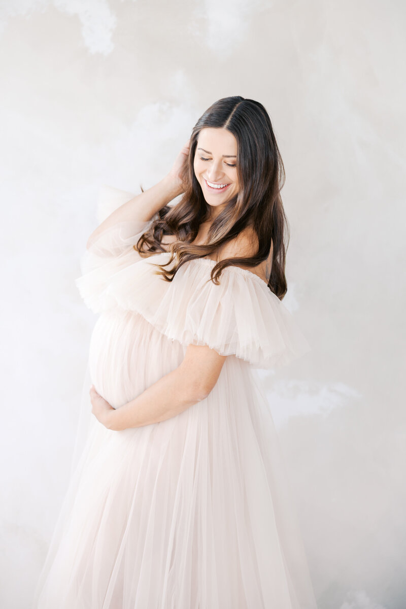 Woman wearing tulle maternity gown during her in studio minneapolis photography session with angela watts photography.