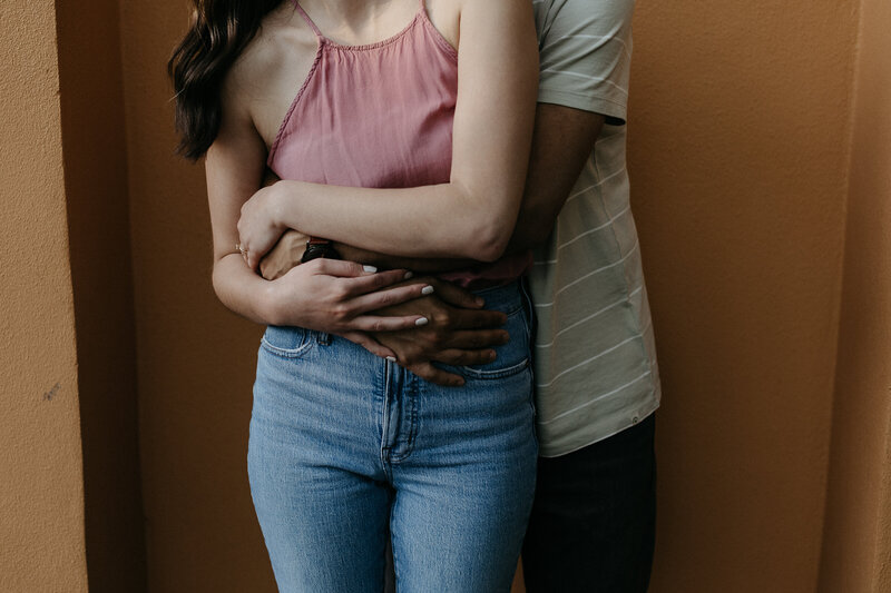 A man hugs his partner from behind.