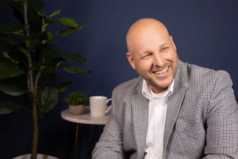 Man smiling looking to the right wearing a white shirt and blazer