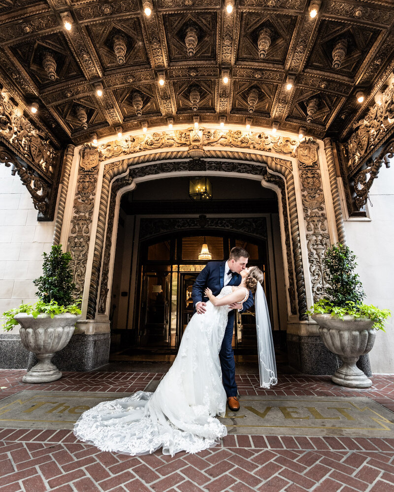 Portrait of groom dipping bride at the entrance to the Roosevelt Hotel in New Orleans