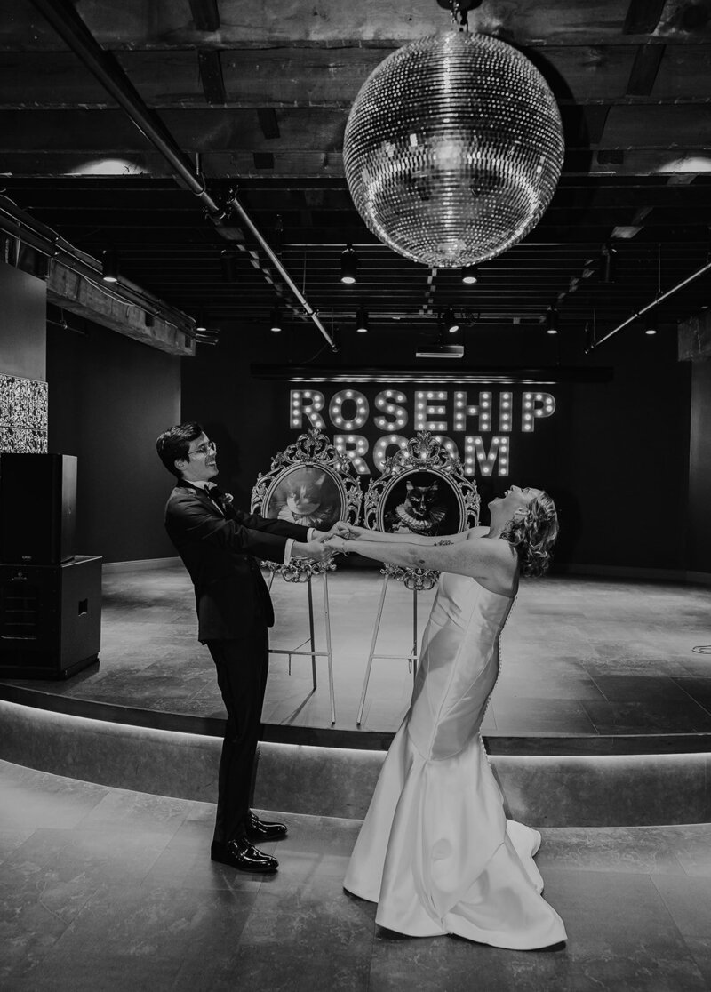 black and white photo of bride and groom dancing and having fun at wedding reception