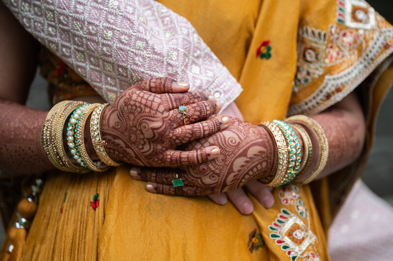 Close up of a bride's hands with henna tattoos while holding onto her grooms arm
