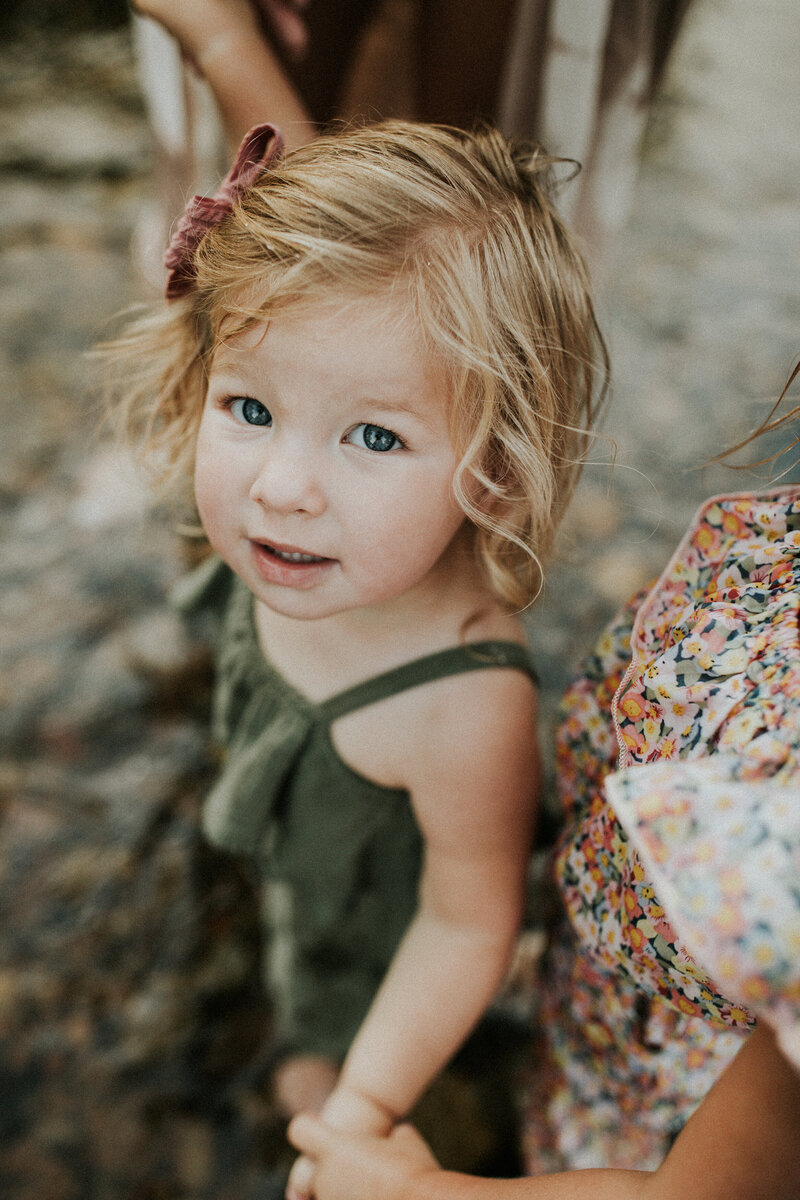 A girl toddler looks up smiling at the camera