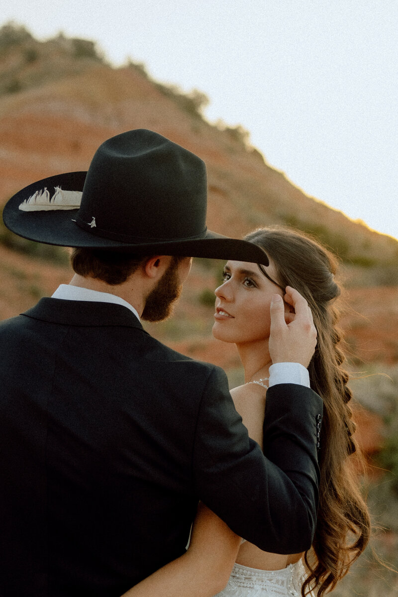 groom brushing brides hair away from her face at their elopement in texas