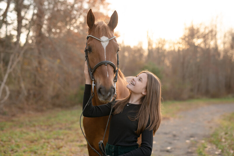 girl smiling and looking at horse