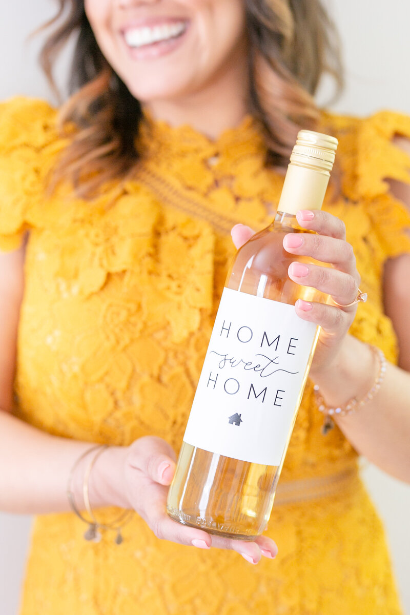Orlando REALTOR holding wine bottle with two hands with a tan dress