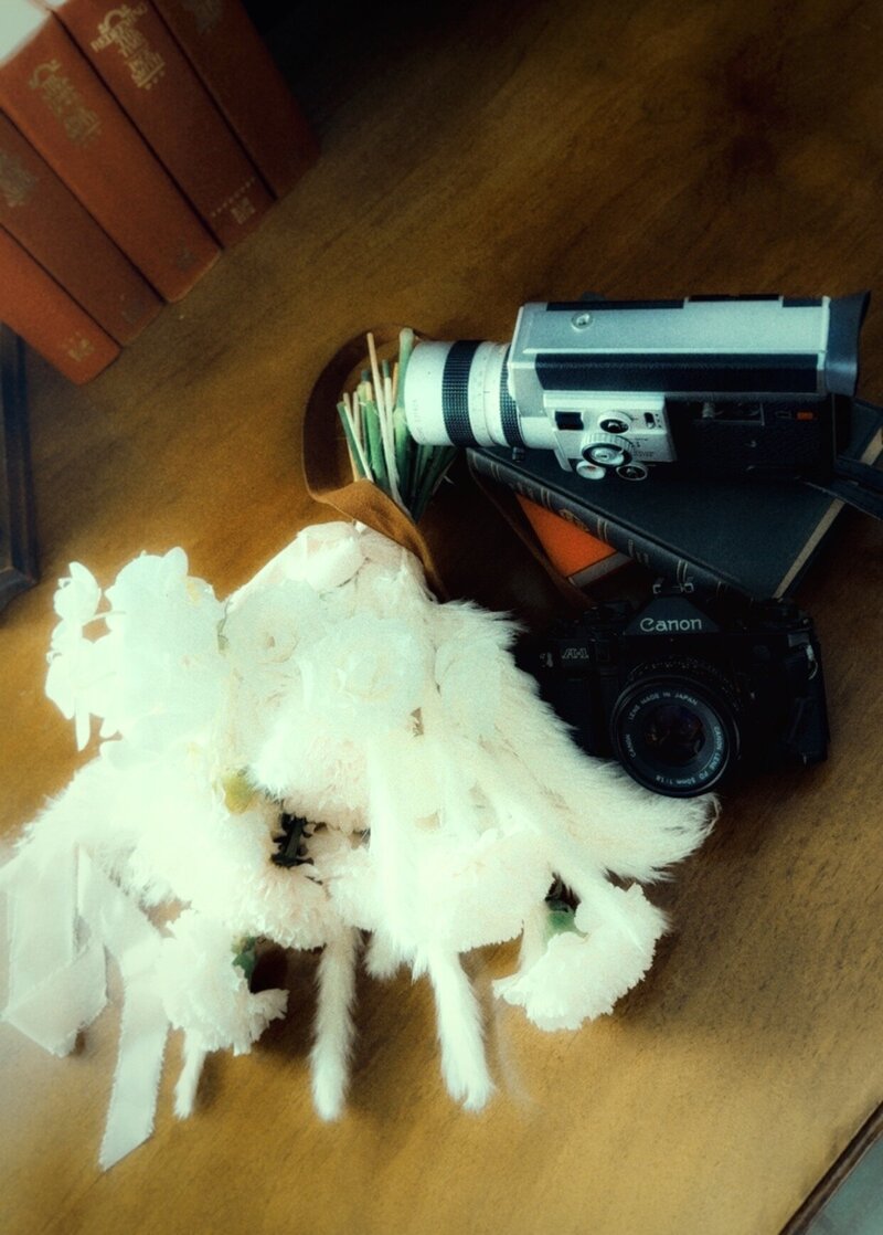 A high-angle shot of a black and silver vintage Canon Super 8 movie camera resting on a wooden floor