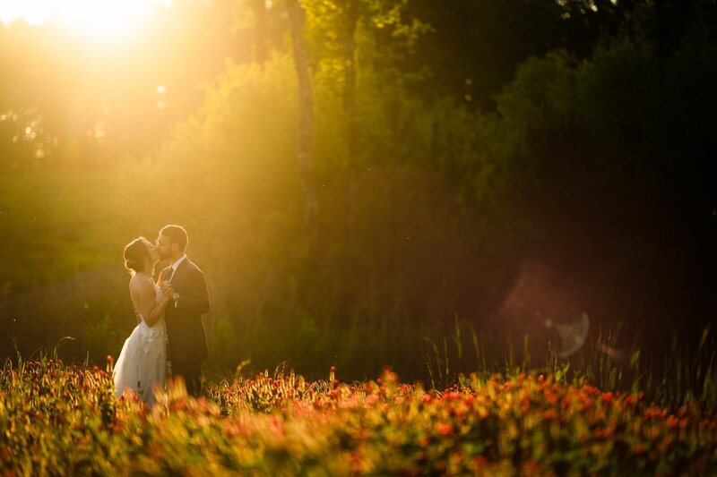 A bride and groom cutting their wedding cake as confetti falls behind them.
