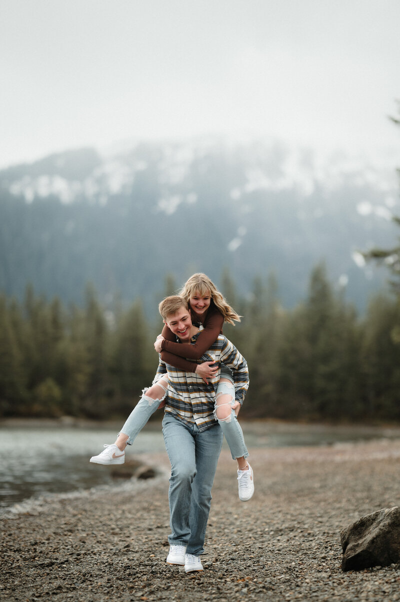 couple piggybacking on a beach in juneau alaska